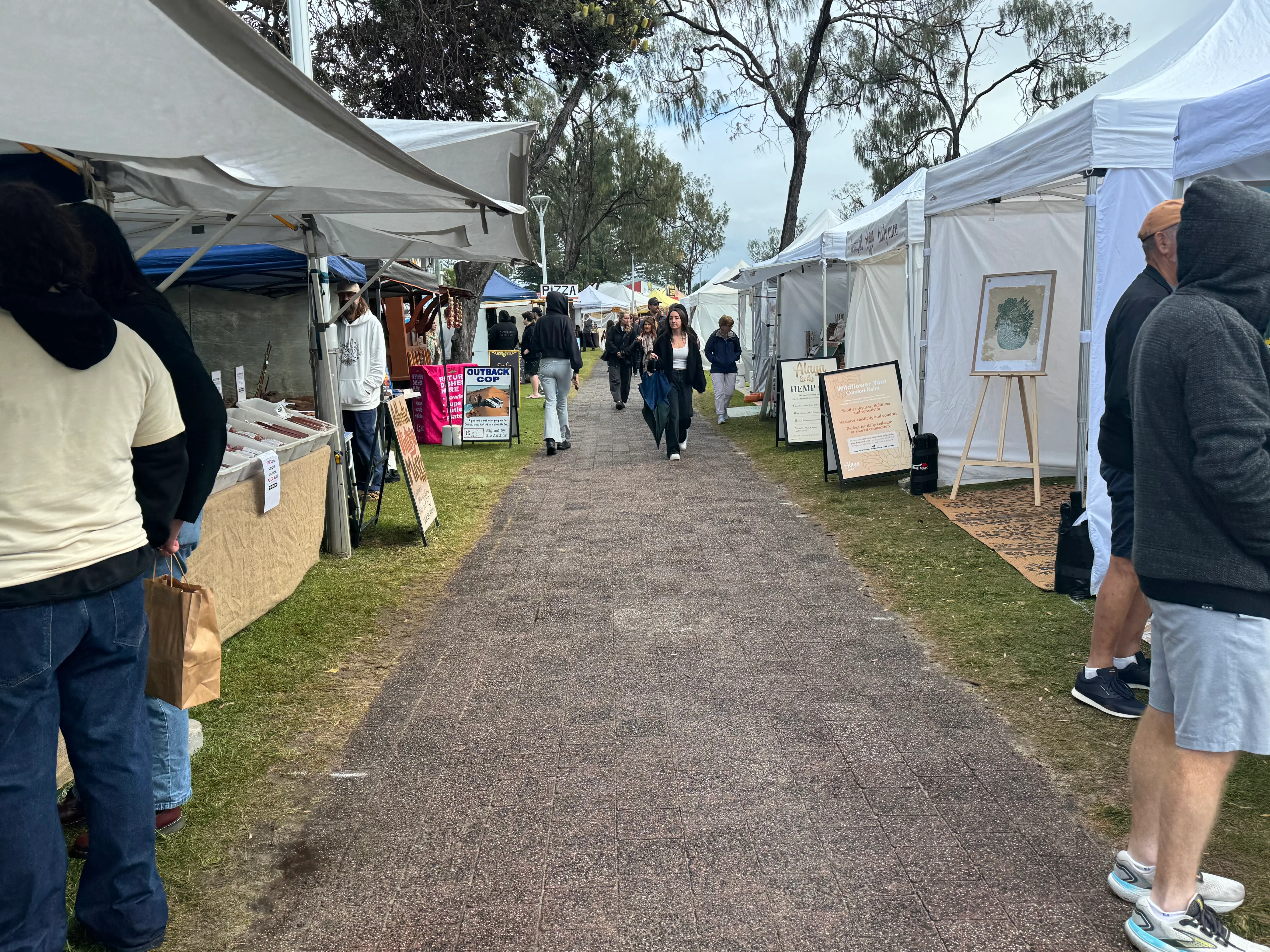 People walking between food and maker stalls at Byron Community Market on a Sunday morning