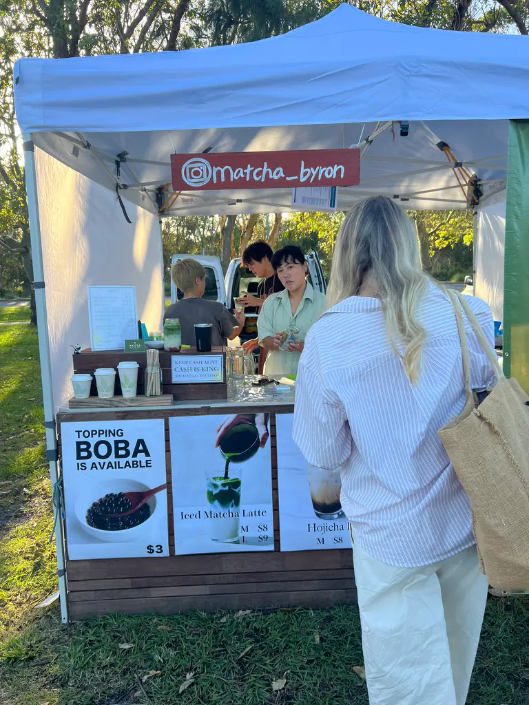 The Matcha Byron stall at the Byron Bay Farmers Market with an iced matcha latte menu and a 'boba available' sign