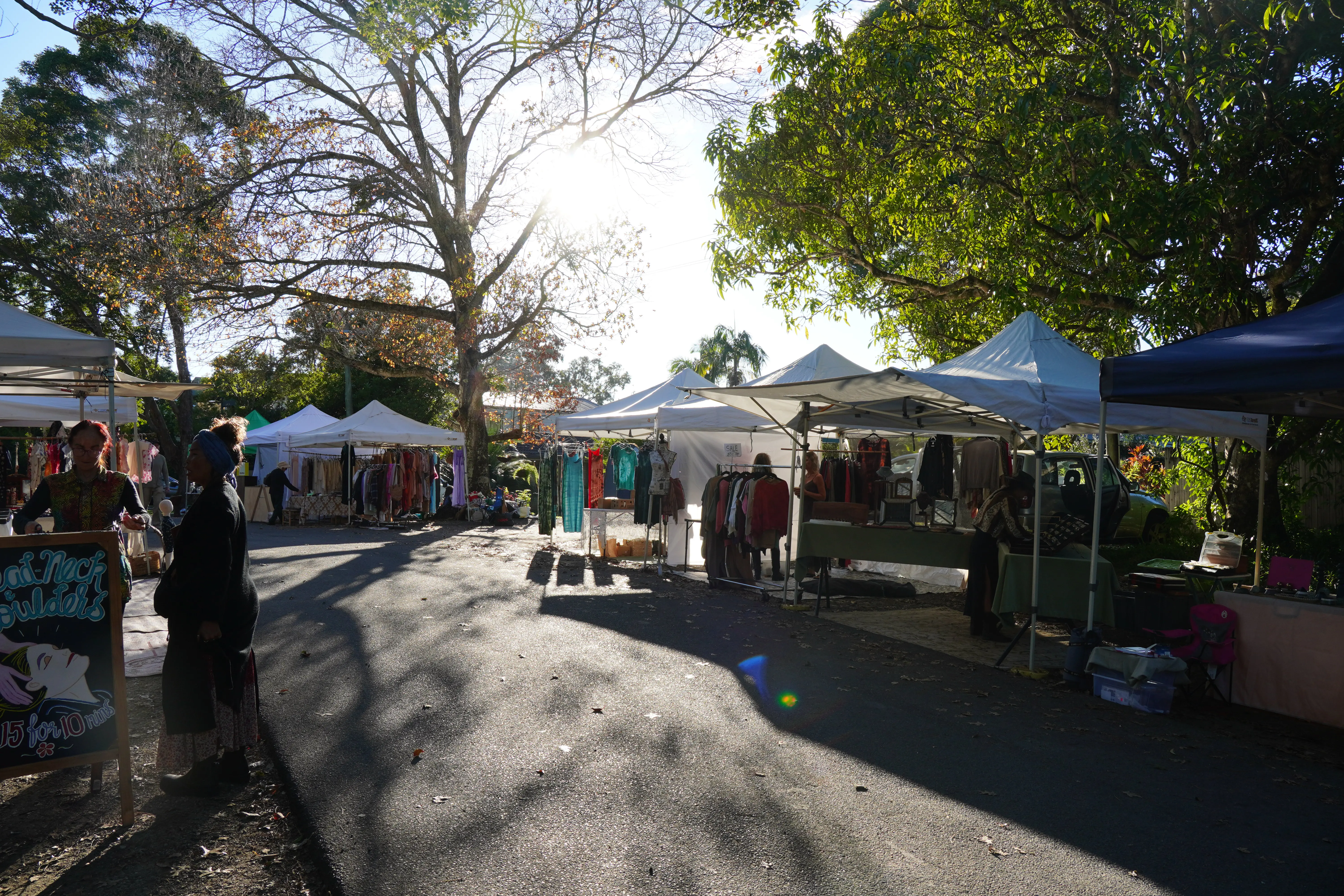 A wider street view of stalls and people at Mullumbimby Community Markets