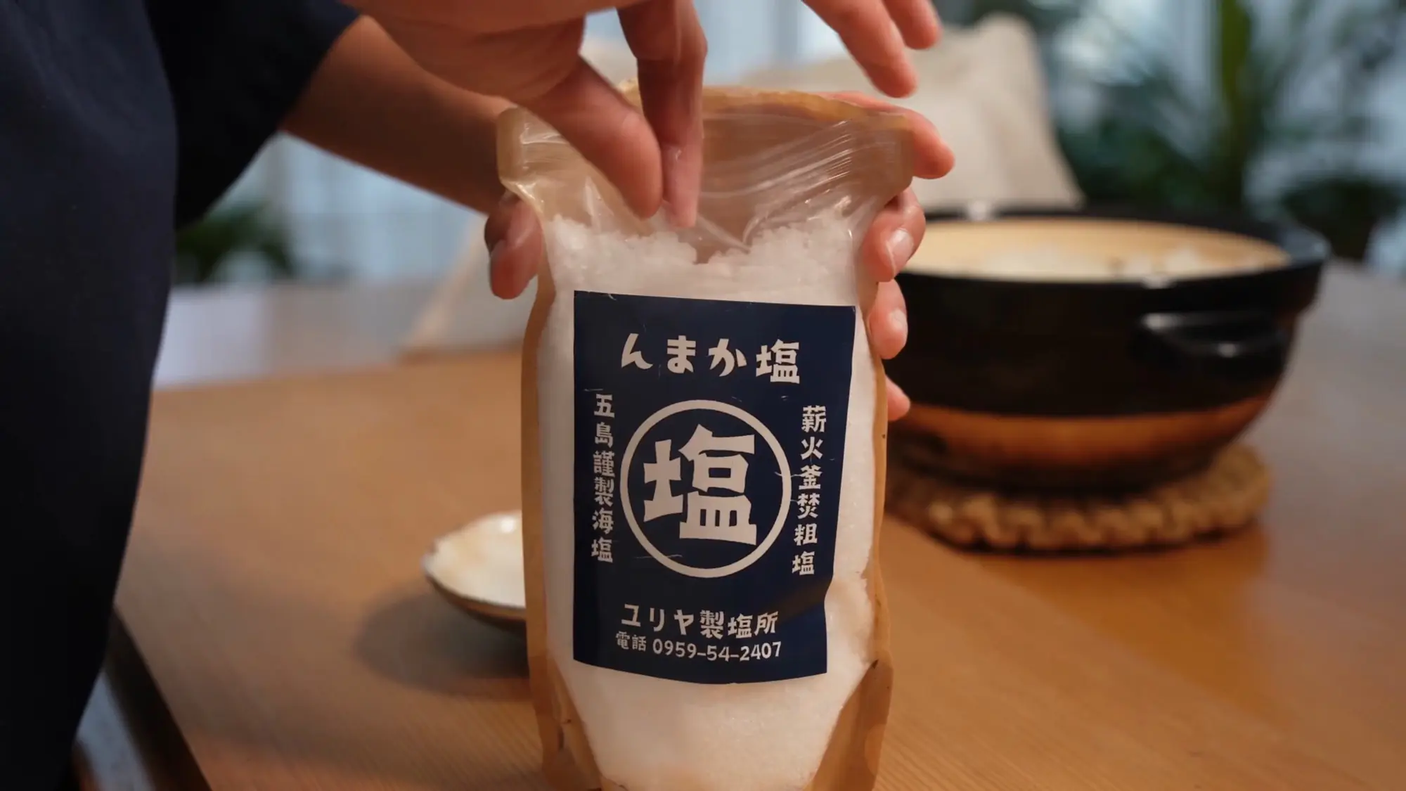 A bag of artisanal Japanese sea salt from a small Goto Islands saltworks held over a wooden table